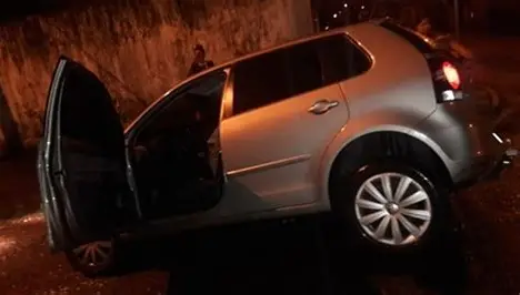 Carro fica inclinado após roda cair em buraco em rua de Pindamonhangaba